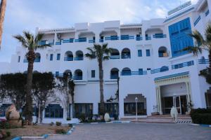 un bâtiment blanc avec des palmiers devant lui dans l'établissement Hotel Le Khalife, à Hammamet