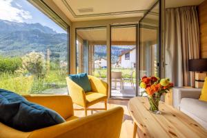 una sala de estar con una mesa con un jarrón de flores en SWISSPEAK Resorts Meiringen, en Meiringen