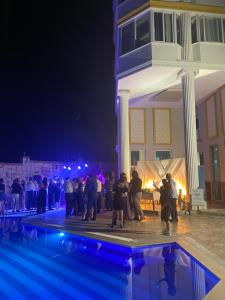 un grupo de personas de pie alrededor de una piscina por la noche en Adil Butik Otel, en Didim
