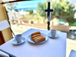 貝納加爾彭塔的住宿－Apartamanto Frente a la Playa, Torre de Benagalbon，一张桌子,上面放着两杯咖啡和一盘食物