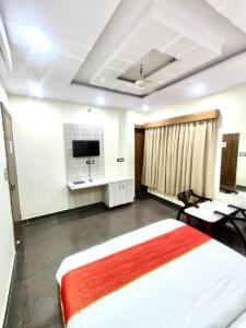 1 dormitorio con 1 cama, escritorio y TV en Hotel Sarovar Regenta, en Mathura
