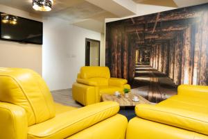 a living room with yellow furniture and a wall mural at DunaCentroom in Dunaújváros