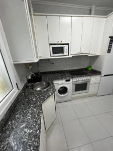 a kitchen with white cabinets and a sink and a microwave at 3 habitaciones reformado y centrico in Santander +14 photos