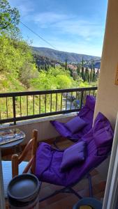 a balcony with purple cushioned chairs and a table at Jolie vue surplomb village grand studio Phannie 50m cures parking et Wi-Fi haut débit in Amélie-les-Bains-Palalda