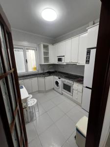a kitchen with white cabinets and a stove top oven at 3 habitaciones reformado y centrico in Santander