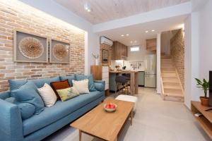 ein Wohnzimmer mit einem blauen Sofa und einer Ziegelwand in der Unterkunft La Signora Cofineta by Anita Holiday Homes in Korfu-Stadt
