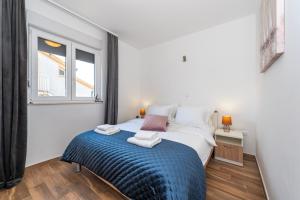 een slaapkamer met een bed met een blauwe deken en een raam bij First Choice Apartment Rogoznica in Rogoznica