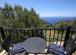 a table and chairs on a balcony with the ocean at Moratika Farmhouse in Agios Kirykos +2 photos