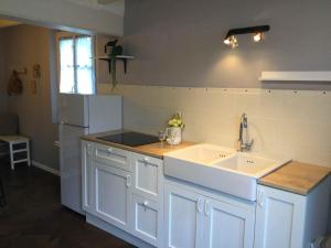 a white kitchen with a sink and a refrigerator at Les Perdrielles in Fontevraud-l'Abbaye +3 photos