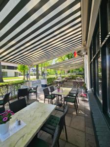a patio with tables and chairs under awning at De Arcense Herberg in Arcen