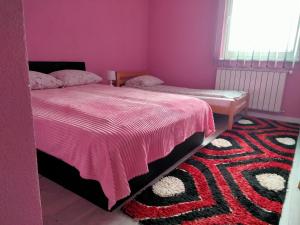 a bedroom with two beds and a rug at Apartman Kumalic in Sanski most