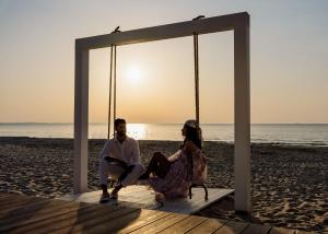 un hombre y una mujer sentados en un columpio en la playa en The SKY by Wave Międzyzdroje Resort&SPA en Międzyzdroje