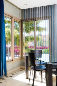 a dining room with a table and chairs and windows at Coin Lumineux à Prestigia Piscine - vue Atlas in Marrakech