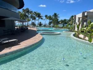 a pool at a resort with palm trees at Casa G9 - Naluum Residence in Passo de Camarajibe