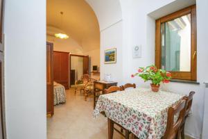 een eetkamer met een tafel met een vaas met bloemen erop bij One bedroom house with sea view enclosed garden and wifi at Sorrento 1 km away from the beach in Sorrento