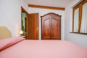 een slaapkamer met een roze bed en een houten deur bij One bedroom apartement with sea view enclosed garden and wifi at Sorrento 1 km away from the beach in Sorrento