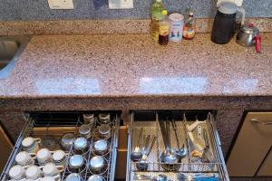 a kitchen counter with an open dish rack with utensils at Green House with kitchen in Srinagar