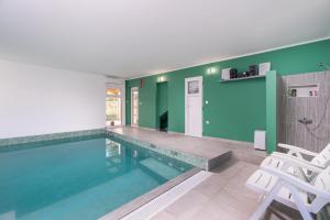 a swimming pool with two white chairs and a blue wall at Villa Roko in Vir