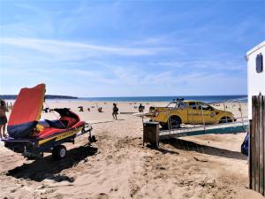 ein gelbes Auto, das am Strand neben einem Pier parkt in der Unterkunft Alouette Piscines chauffees in Saint-Hilaire-de-Talmont