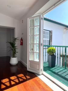 Une porte ouverte s'ouvre sur un balcon orné de plantes en pot. dans l'établissement Casa de Foro, à Angra do Heroísmo