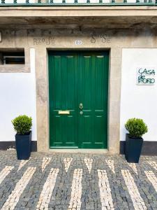 une porte verte sur un bâtiment avec deux plantes en pot dans l'établissement Casa de Foro, à Angra do Heroísmo
