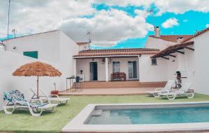 uma casa com uma piscina com cadeiras e um guarda-sol em Casa da Espiga - Alentejo em Trigaches