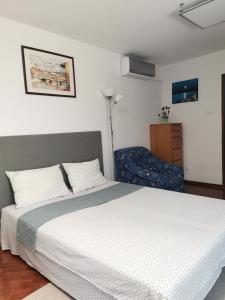 a bedroom with a white bed and a chair at Miri's House in Eforie Sud