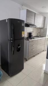 a kitchen with a black refrigerator in a kitchen at Acogedor apartamento La Nubia in Manizales