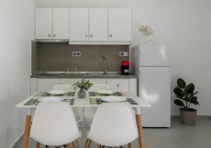 a kitchen with a table with white chairs and a refrigerator at The Port in Porto Koufo