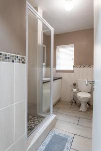 ein Bad mit einer Dusche und einem WC in der Unterkunft Jeffreys Bay Villas on The Beach in Jeffreys Bay