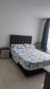 a bed with a comforter and a chair in a bedroom at Acogedor apartamento La Nubia in Manizales