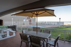 a patio with a table and chairs and an umbrella at Jeffreys Bay Villas on The Beach in Jeffreys Bay