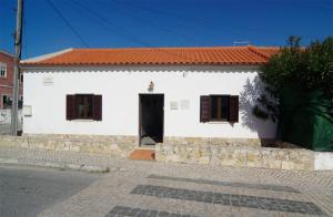a white house with a black door and windows at Casa do Sol Nascente in Foz do Arelho