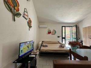 Kleines Zimmer mit einem Bett und einem TV in der Unterkunft Appartamenti magnolie-La pineta in Valledoria