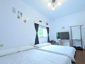 2 Betten in einem weißen Zimmer mit Fenster in der Unterkunft A-Lang Homestay in Lanyu
