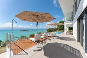 een patio met stoelen en een parasol en de oceaan bij Guacana in Le Gosier