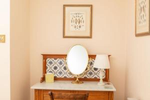 einen Schminktisch mit einem Spiegel und einer Lampe in der Unterkunft Balnagown Estates Peat Cottage in Kildary + 22 Fotos