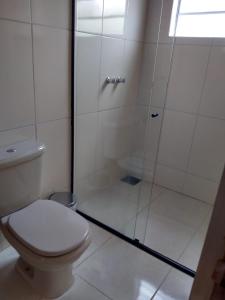 a bathroom with a toilet and a glass shower at Chalés Excalibur in São Thomé das Letras