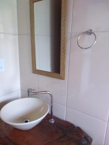 un lavandino bianco in un bagno con specchio di Chalés Excalibur a São Thomé das Letras