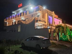 a car parked in front of a building with christmas lights at 26 Number Bus Stop Guest House in Islamabad