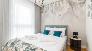 a bedroom with a bed with white sheets and blue pillows at Apartamenty Sun & Snow Resort Jantar in Jantar