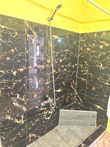 a shower in a bathroom with a black marble wall at Villa Naoual in Moulay Bousselham