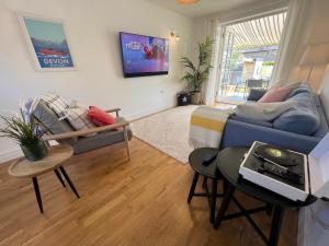 a living room with a blue couch and a table at Manuka Cottage, stylish property with hot tub in Stoke Gabriel
