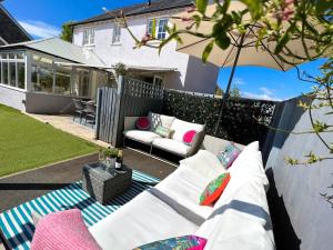a patio with a white couch and an umbrella at Manuka Cottage, stylish property with hot tub in Stoke Gabriel