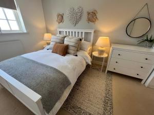 a bedroom with a bed and a dresser with a mirror at Manuka Cottage, stylish property with hot tub in Stoke Gabriel