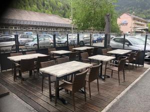a row of tables and chairs on a wooden deck at Hôtel Le Commerce in Modane