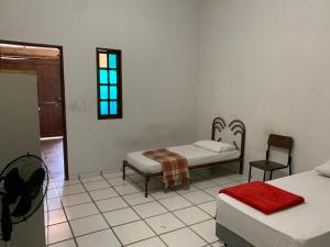 a bedroom with two beds and a chair and a window at Hotel economic eldorado in Sorocaba