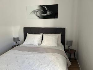 a bedroom with a bed with a black headboard and two lamps at Apartments Mia in Bibinje