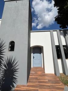 a white building with a door and a wooden walkway at Astor Hostel in Campinas