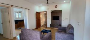 a living room with two chairs and a tv at The Heritage Serviced Apartments in Mandya
